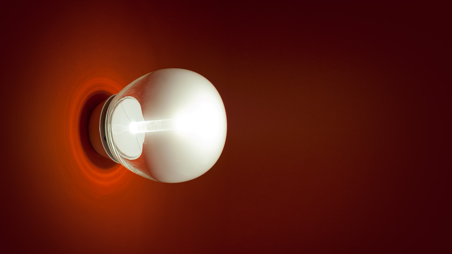 Three Artemide Empatia wall/ceiling lamps in decreasing sizes, emitting soft white spherical glow against a dark background