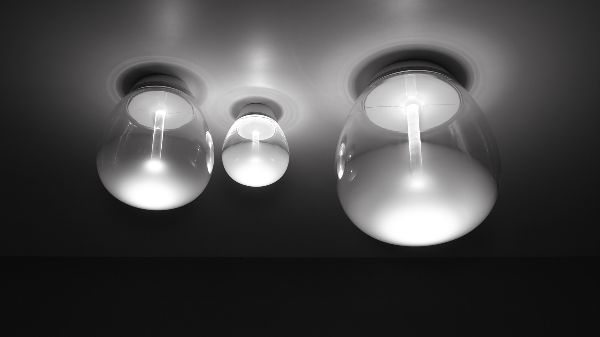 Artemide Empatia wall/ceiling lamp: opal white spherical diffuser on glass stem, mounted on dark red wall with warm glowing halo
