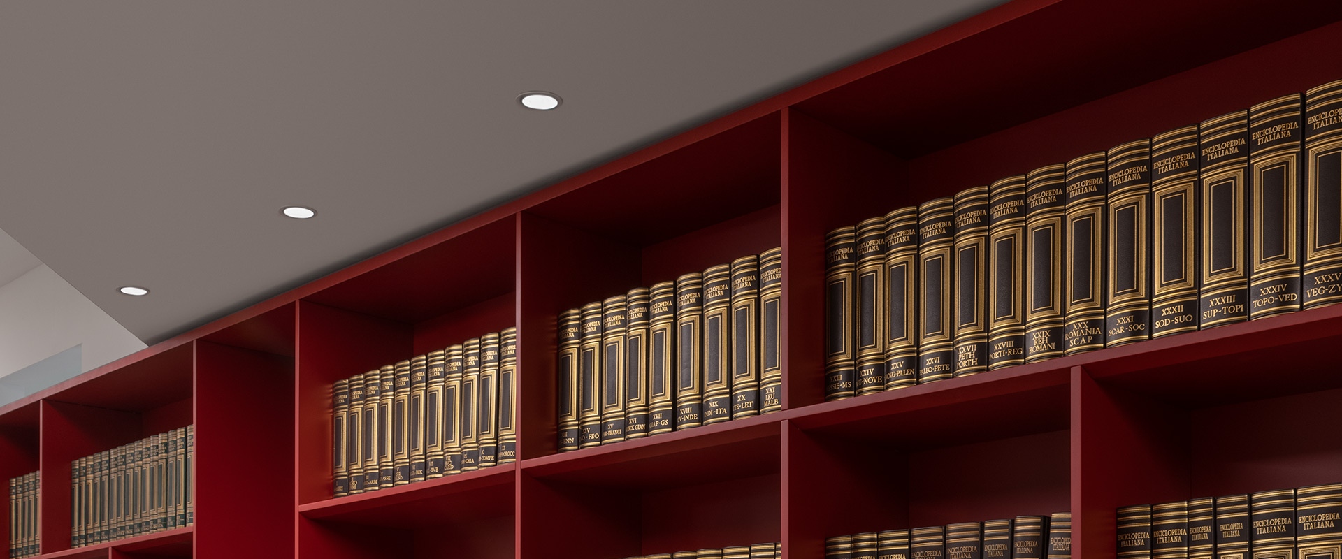 Artemide Everything 80 Trim recessed ceiling spotlights illuminating red library shelves filled with leather-bound books