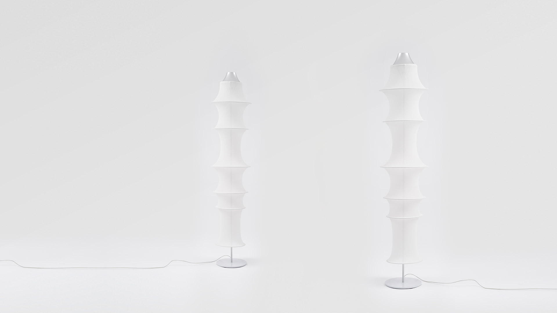 Due lampade da terra Artemide Falkland Terra con diffusori in tessuto bianco sovrapposti su basi metalliche sottili, mostrate affiancate