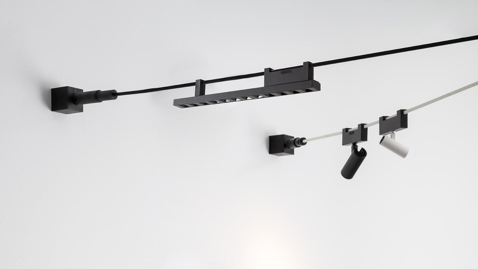 Artemide Funivia system components laid flat: black mounting brackets, connectors, cables, and white linear light bars on white background