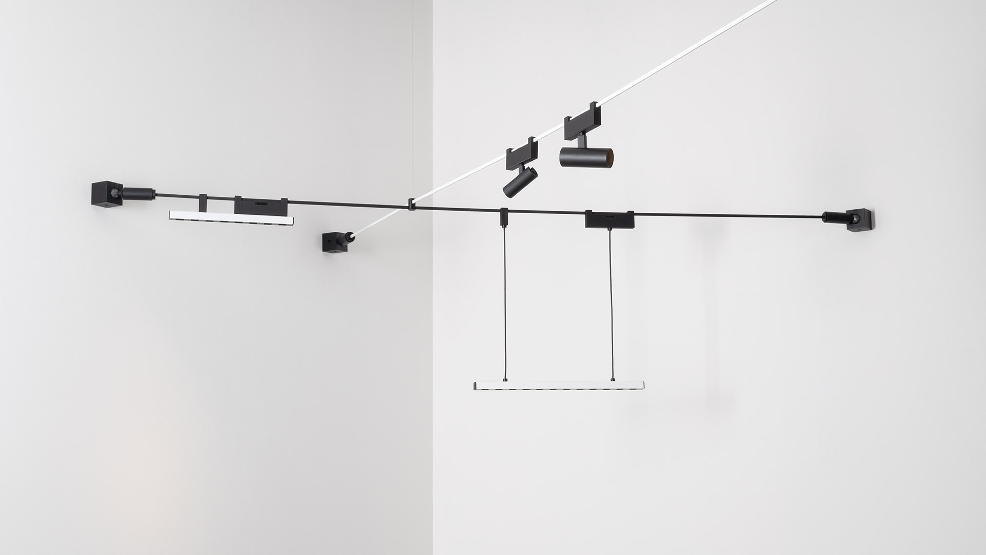 Artemide Funivia system: black ceiling tracks with LED spotlights, red and white cables suspending pendant lights in a gallery space