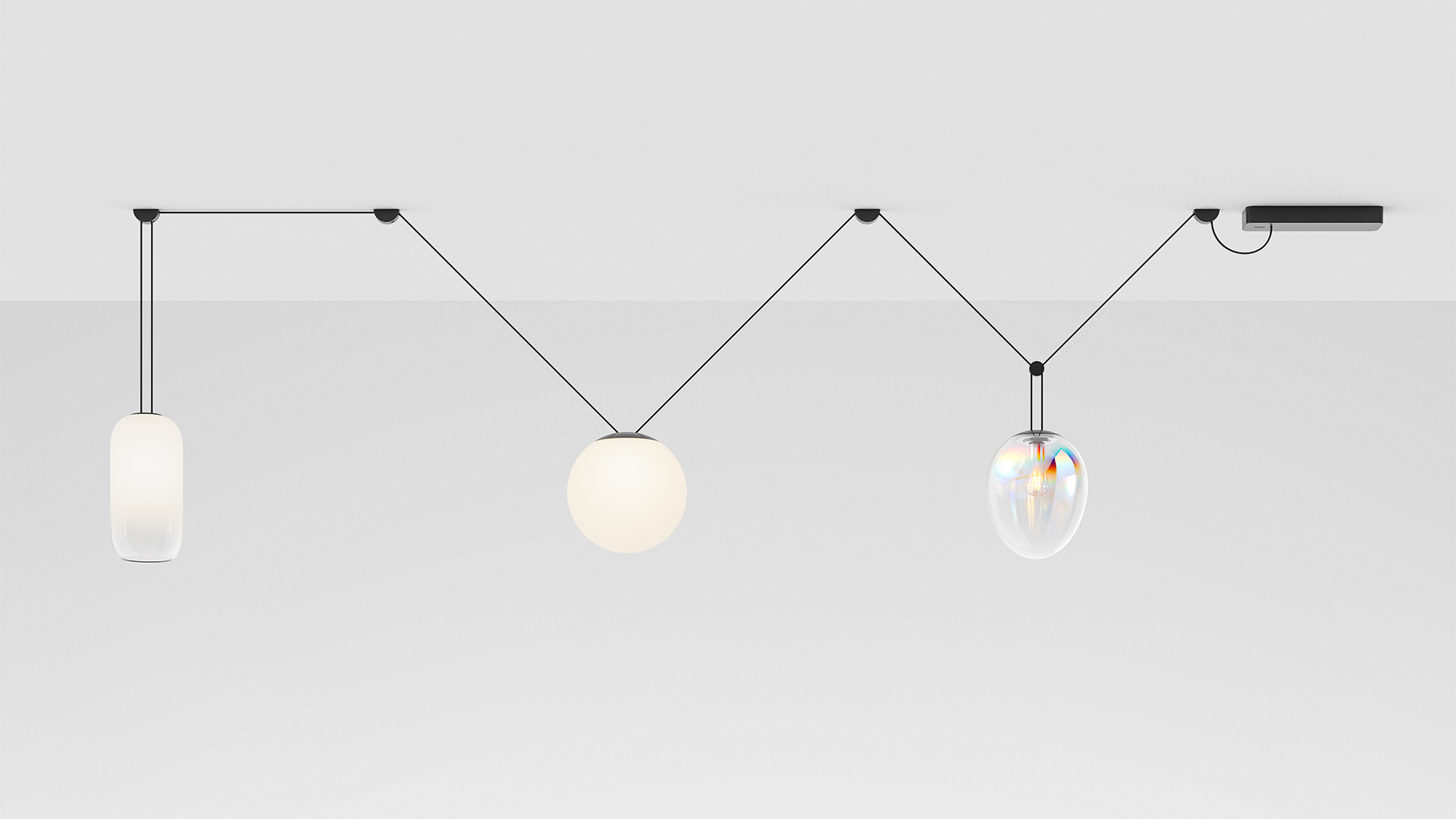 Artemide Funivia system: three pendant lights on black wire cables — cylindrical opal, spherical opal, and iridescent glass shades