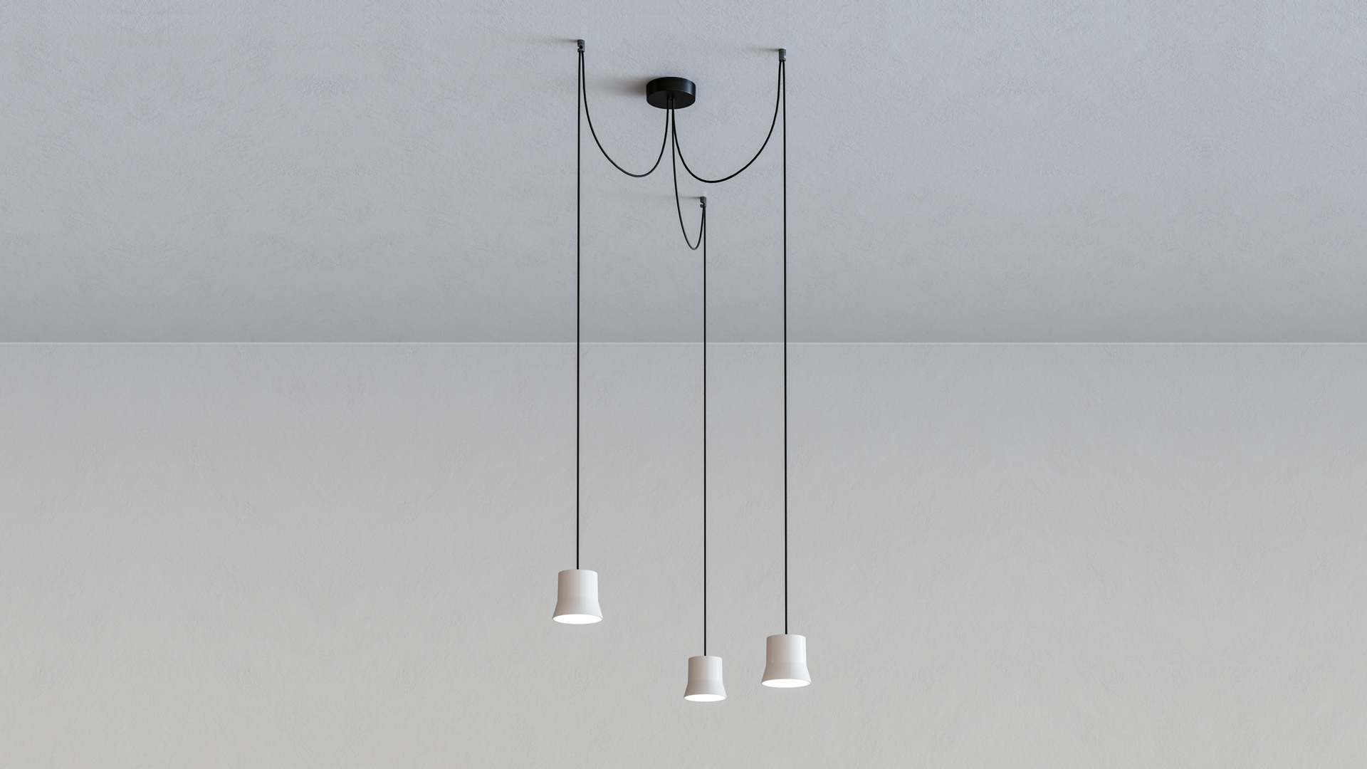Artemide Giò Light Cluster: three white conical pendant lamps hanging at varying heights from black cords on a ceiling canopy