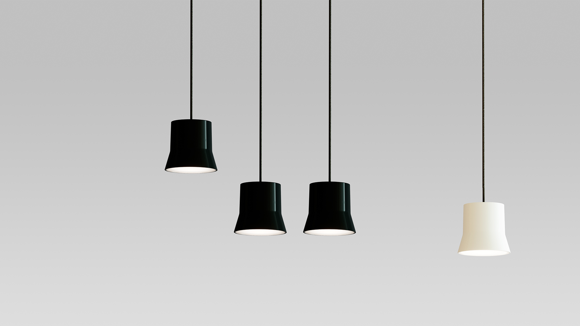 Four Artemide Giò Light suspension pendants: three black and one white, with truncated cone shades hanging at varying heights on thin black cords