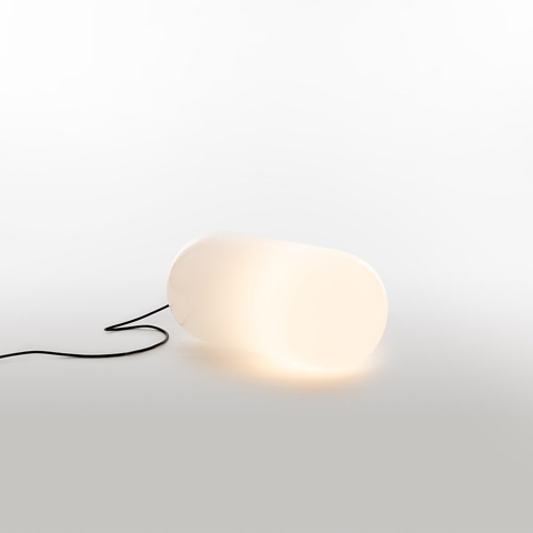 Lampada da terra Artemide Gople Outdoor: diffusore bianco opalino a forma organica di ciottolo che emette luce calda, con cavo nero