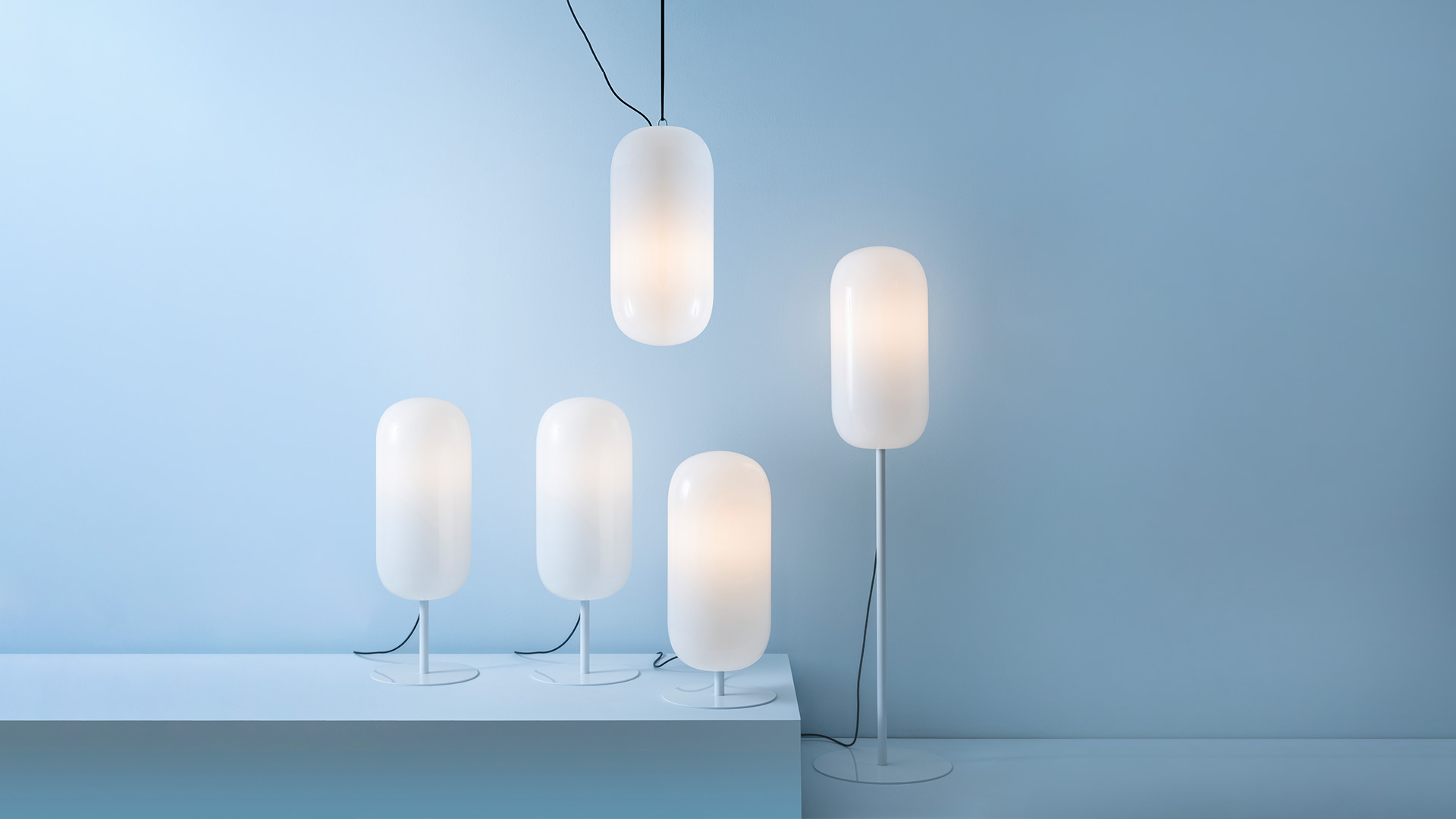 Lampada Artemide Gople Outdoor: diffusore bianco opalino a forma di ciottolo levigato sul pavimento, con luce calda e cavo nero