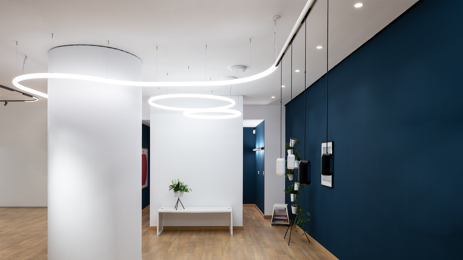 Artemide Gople System: sospensione bianca e due faretti orientabili su binario a soffitto sopra una scrivania minimalista