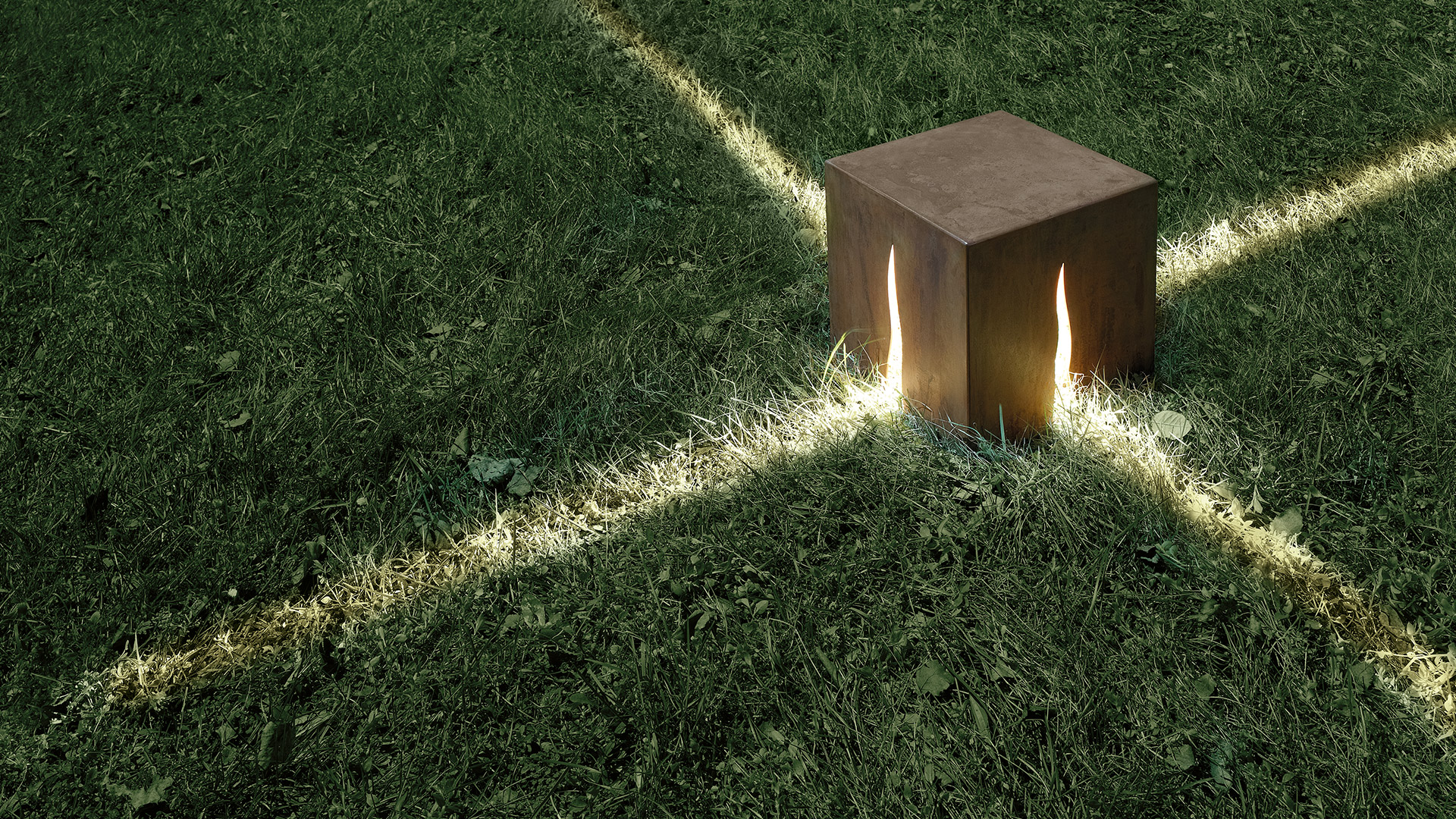 Lampade da esterno cubiche Artemide Granito in finitura scura emettono luce ambrata calda, disposte lungo un vialetto da giardino al crepuscolo