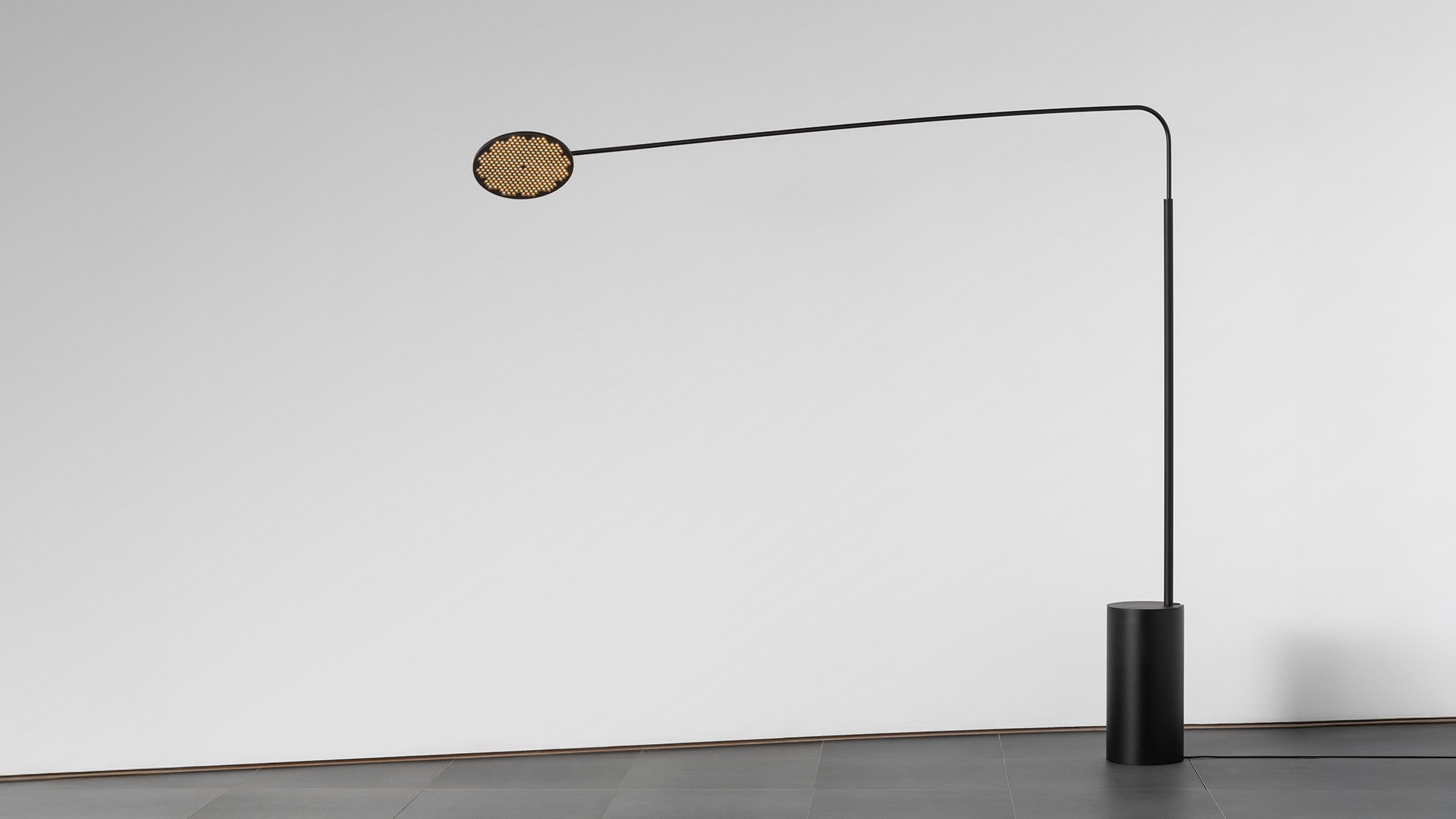 Due lampade a sospensione Artemide Helgoland Archipelago con dischi circolari scuri dotati di griglia LED calda, sospese su cielo blu intenso