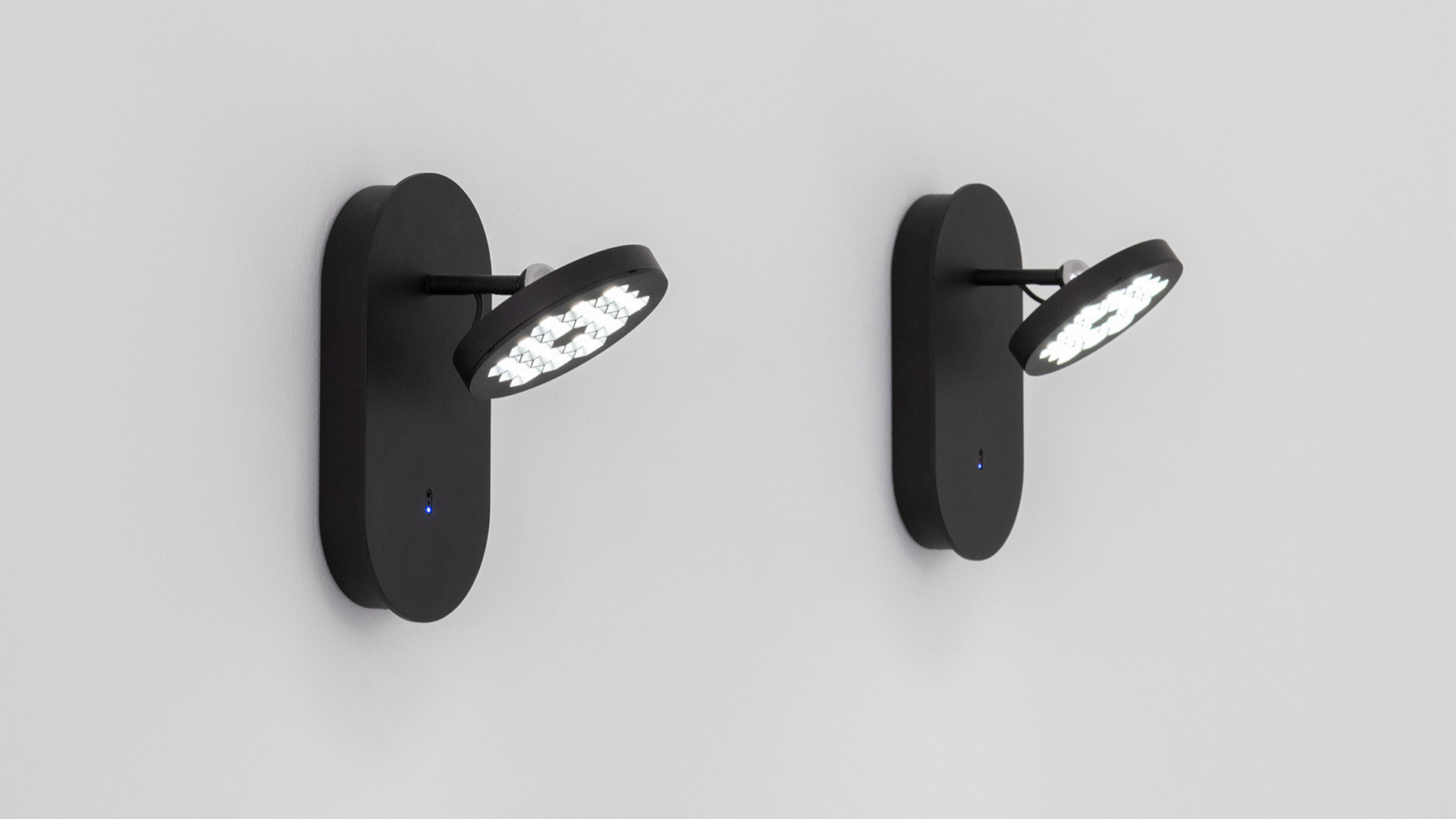 Due applique da parete Artemide Helgoland in nero opaco, con testine LED circolari su bracci orientabili e indicatori blu