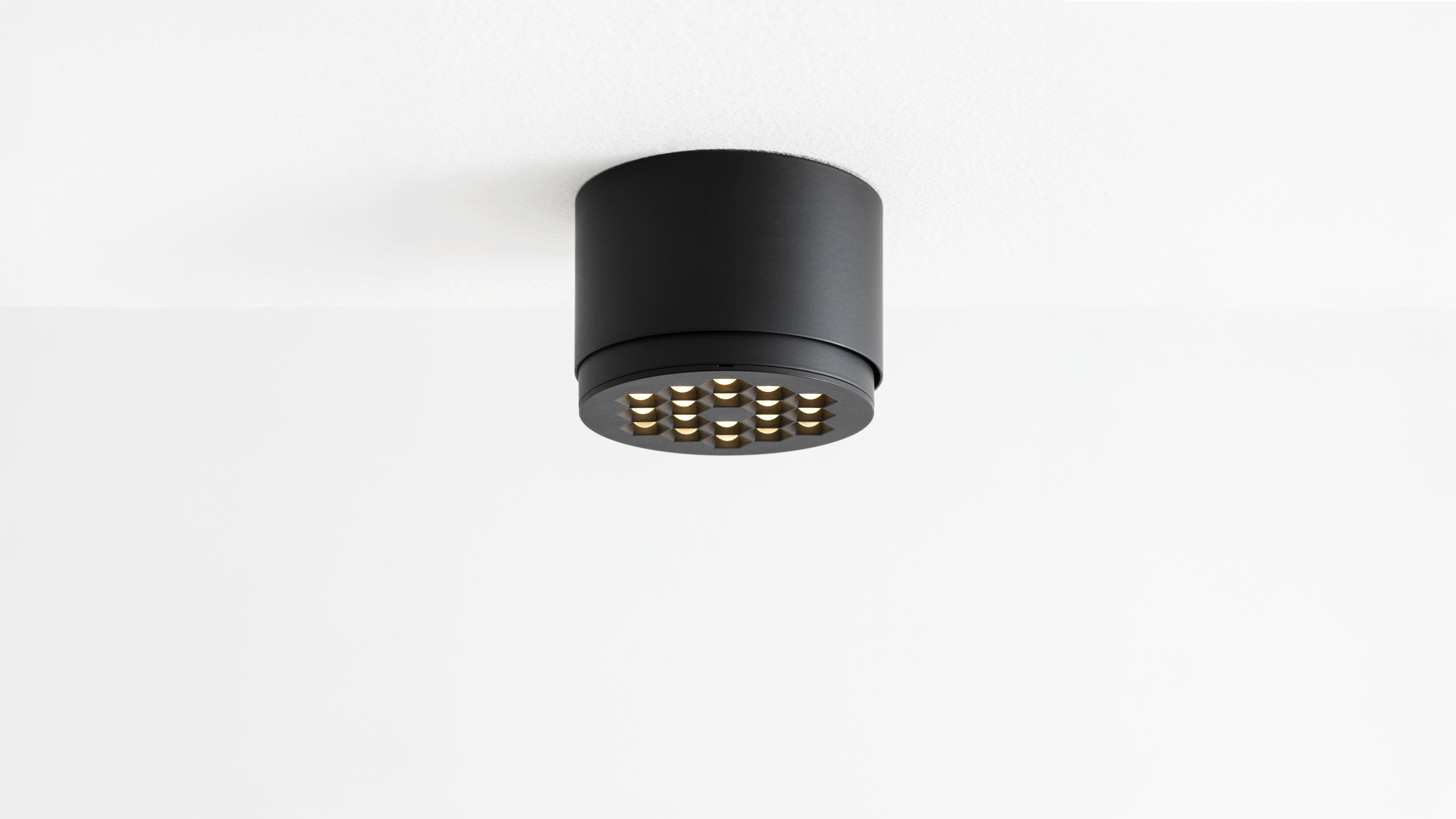 Due faretti LED Artemide Helgoland: sinistra incasso rotondo nero, destra cilindro blu da soffitto con testa nera orientabile