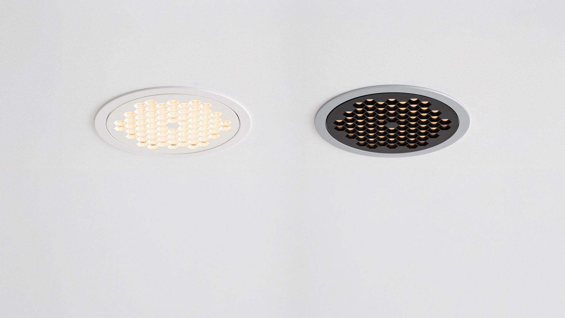 Due faretti da incasso a LED Artemide Helgoland: sinistra con bordo bianco acceso, destra con bordo scuro e griglia a nido d'ape, spento