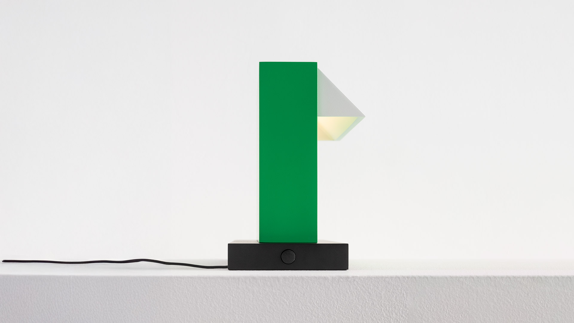 Lampada da tavolo Artemide Hera: corpo rettangolare verde alto con diffusore triangolare su base rettangolare nera con cavo di alimentazione