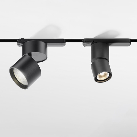 Due faretti Artemide Hoy Spot neri su binario trifase, uno inclinato a sinistra acceso, uno rivolto in avanti illuminato
