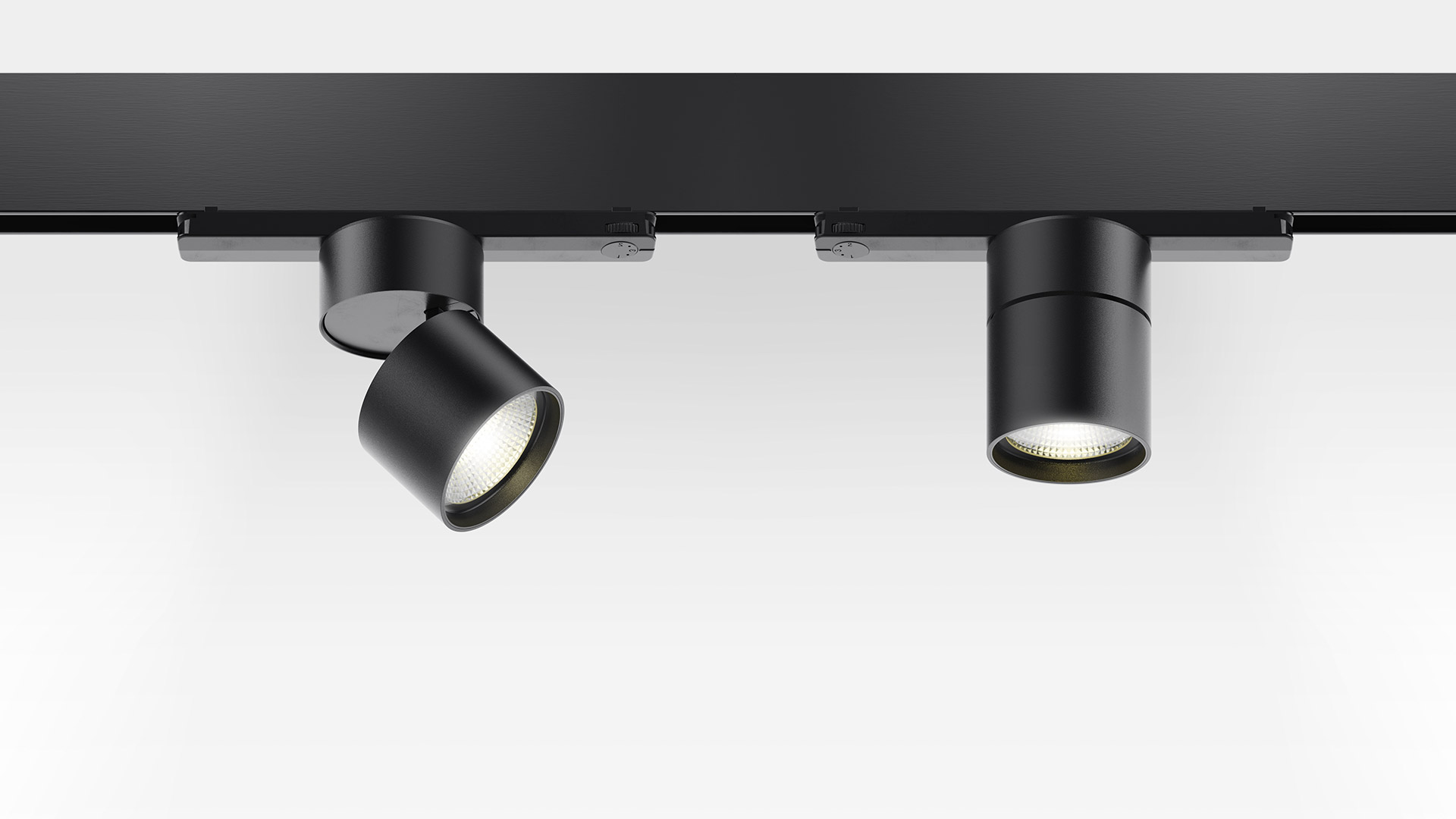 Due faretti Artemide Hoy Spot neri su binario trifase, con teste cilindriche orientabili e luce LED calda