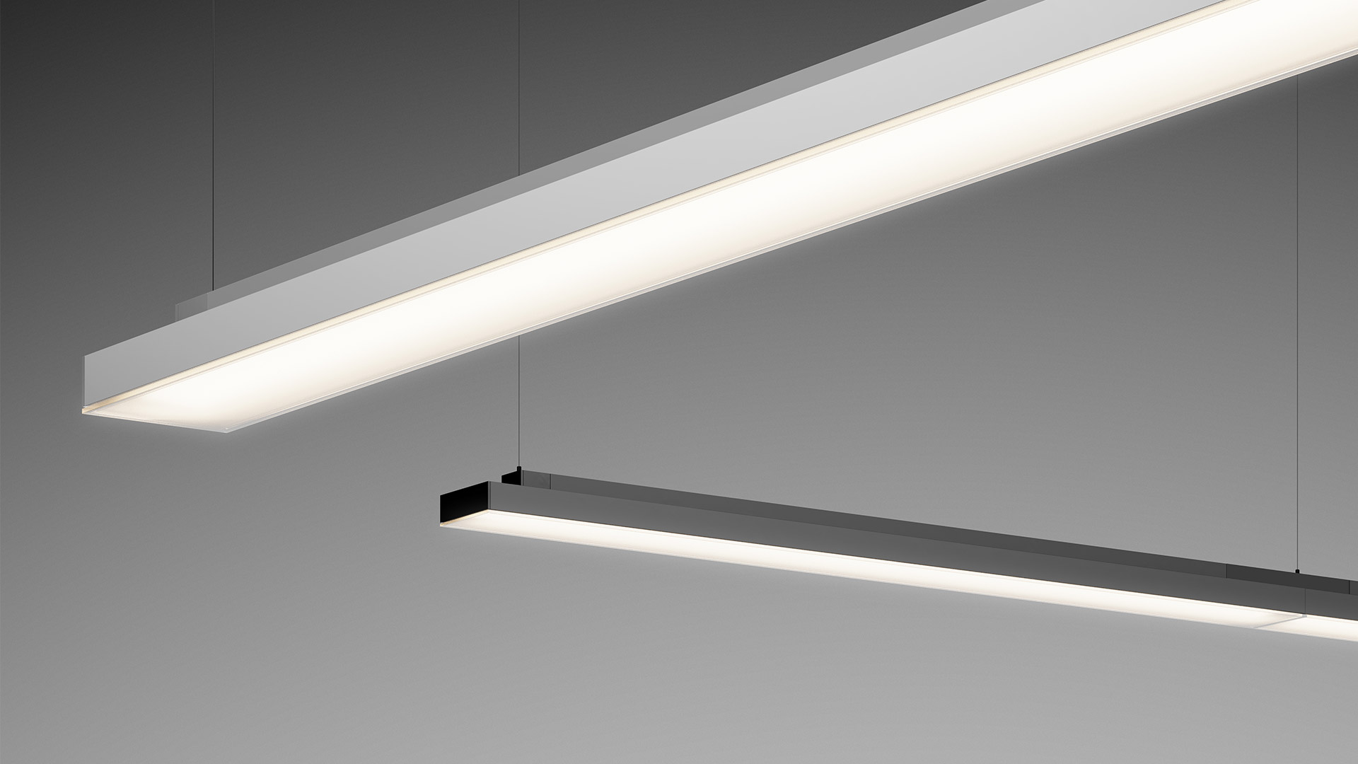 Tre lampade a sospensione cilindriche Artemide Hoy appese al soffitto insieme a strisce LED lineari in un moderno ufficio.