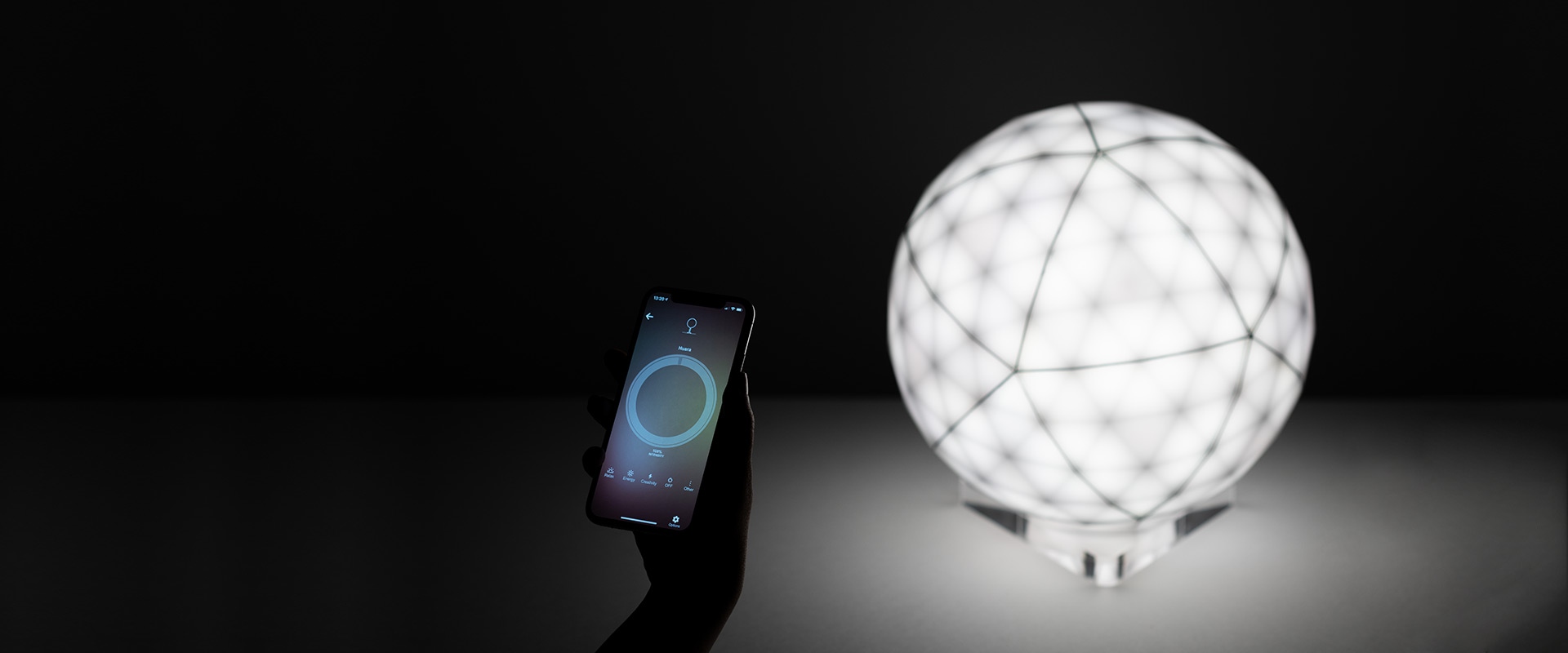 Artemide Huara lamp: faceted spherical design with alternating black and white geometric panels on a transparent crystal base