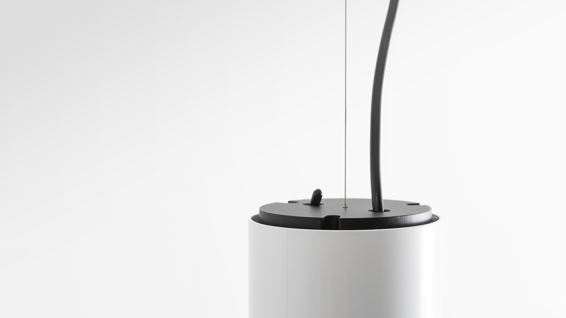 Artemide Ilio pendant and ceiling lamps in white, black, and red, featuring slim cylindrical tubes with wavy cables, shown in multiple configurations