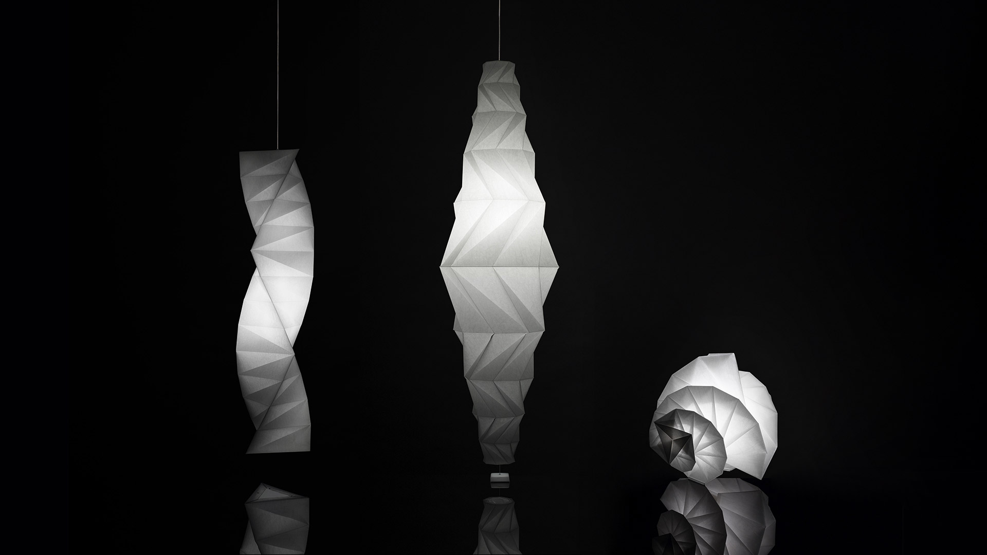 Collezione Artemide In-Ei Issey Miyake: lampade a sospensione e da terra bianche ispirate all'origami con paralumi geometrici pieghettati in una boutique