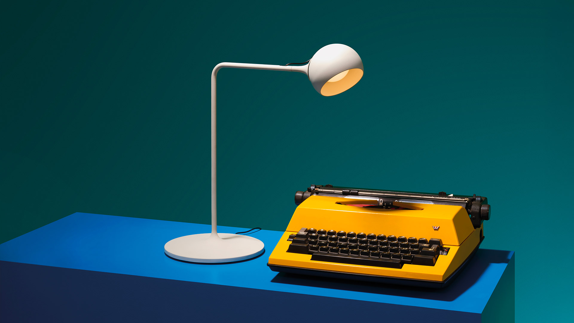 Lampade da terra e da parete Artemide Ixa in arancione e grigio scuro, con bracci regolabili e piccoli diffusori direzionali, che proiettano ombre geometriche