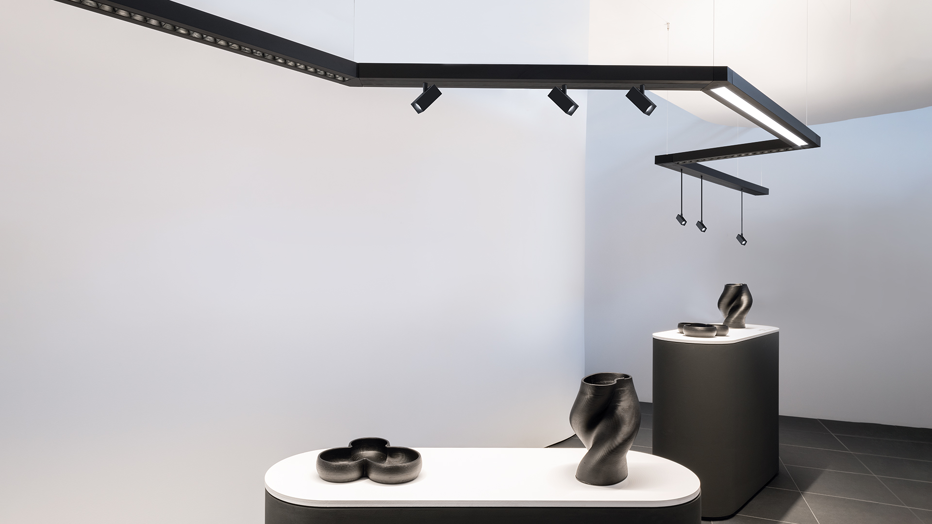 Artemide Katà Métron: sistema di illuminazione a sospensione angolare con diffusori lineari rosso e giallo su binario scuro, con faretto orientabile