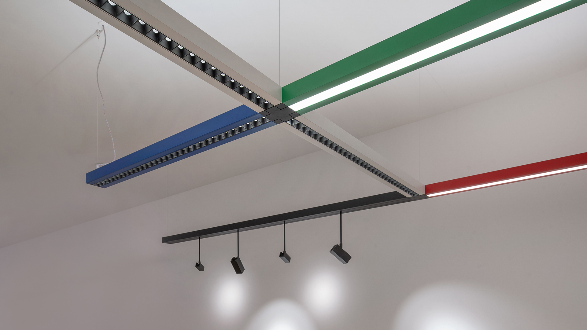 Sistema di illuminazione modulare su binario nero Artemide Katà Métron con faretti e pendenti, che illumina sculture in ceramica scura in uno spazio espositivo