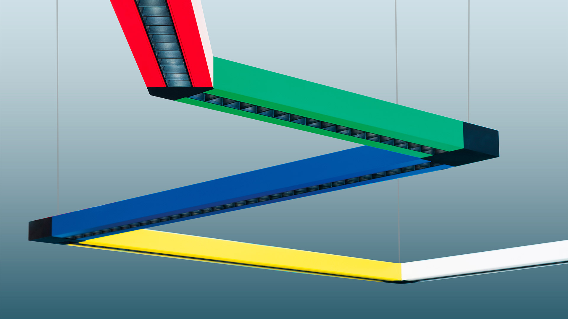 Sistema a binario sospeso Artemide Katà Métron con due faretti LED neri orientabili montati su binari blu e verde