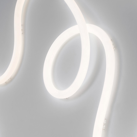 Striscia LED flessibile Artemide La Linea elegantemente curvata in sinuosi anelli, che emette una morbida luce bianca diffusa su una parete grigia