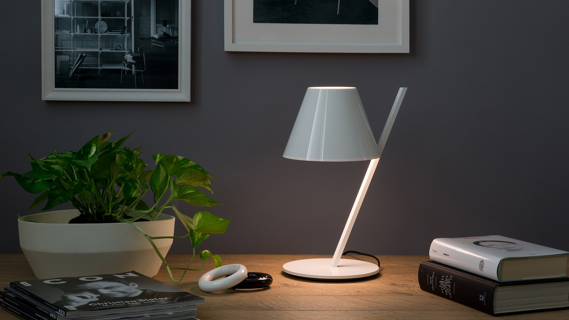 Lampada da tavolo Artemide La Petite: paralume conico nero lucido su stelo diagonale nero, con diffusore interno bianco.