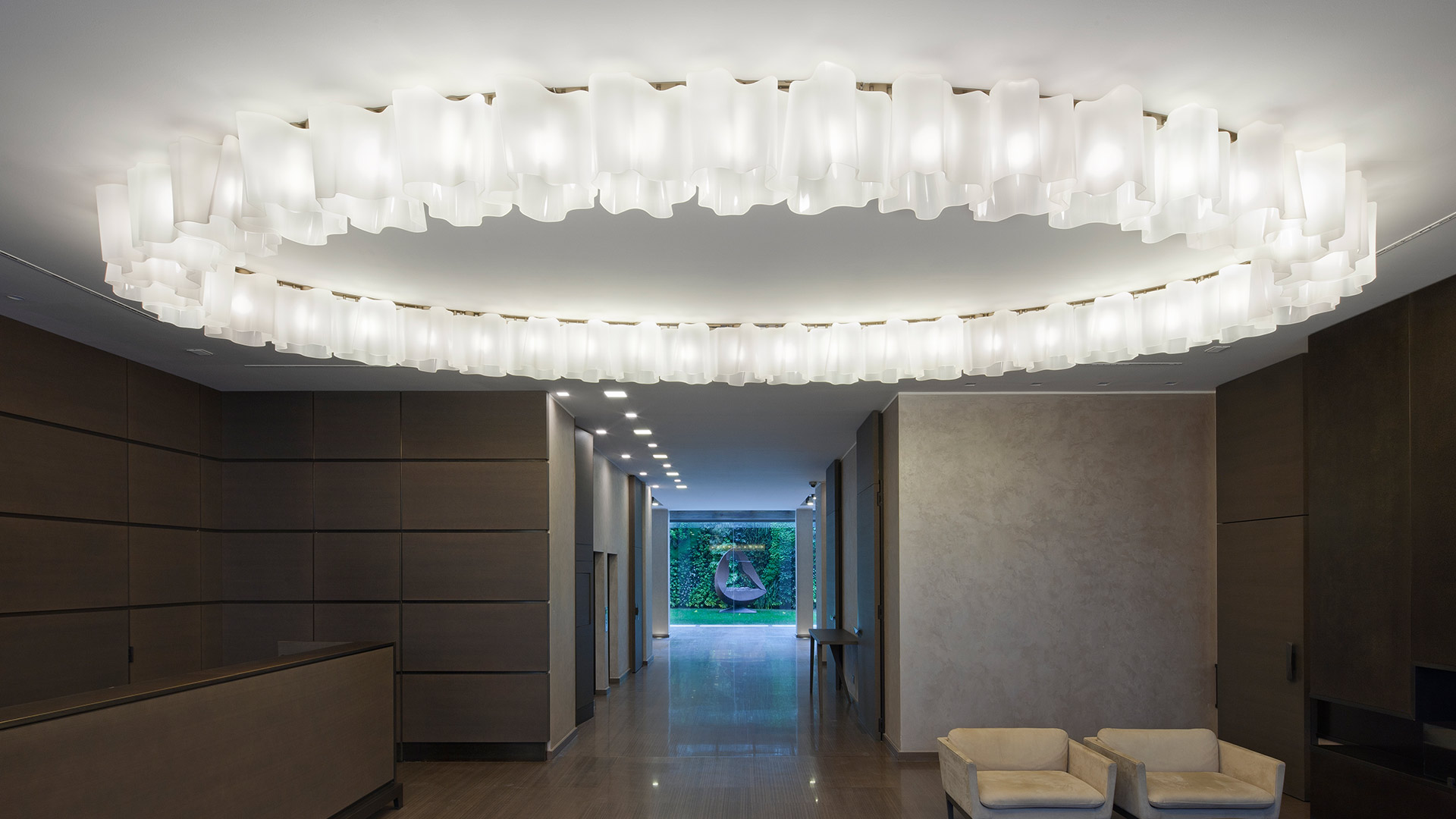 Logico Soffitto di Artemide: due grandi plafoniere ovali con diffusori in vetro satinato illuminano un elegante corridoio di ingresso