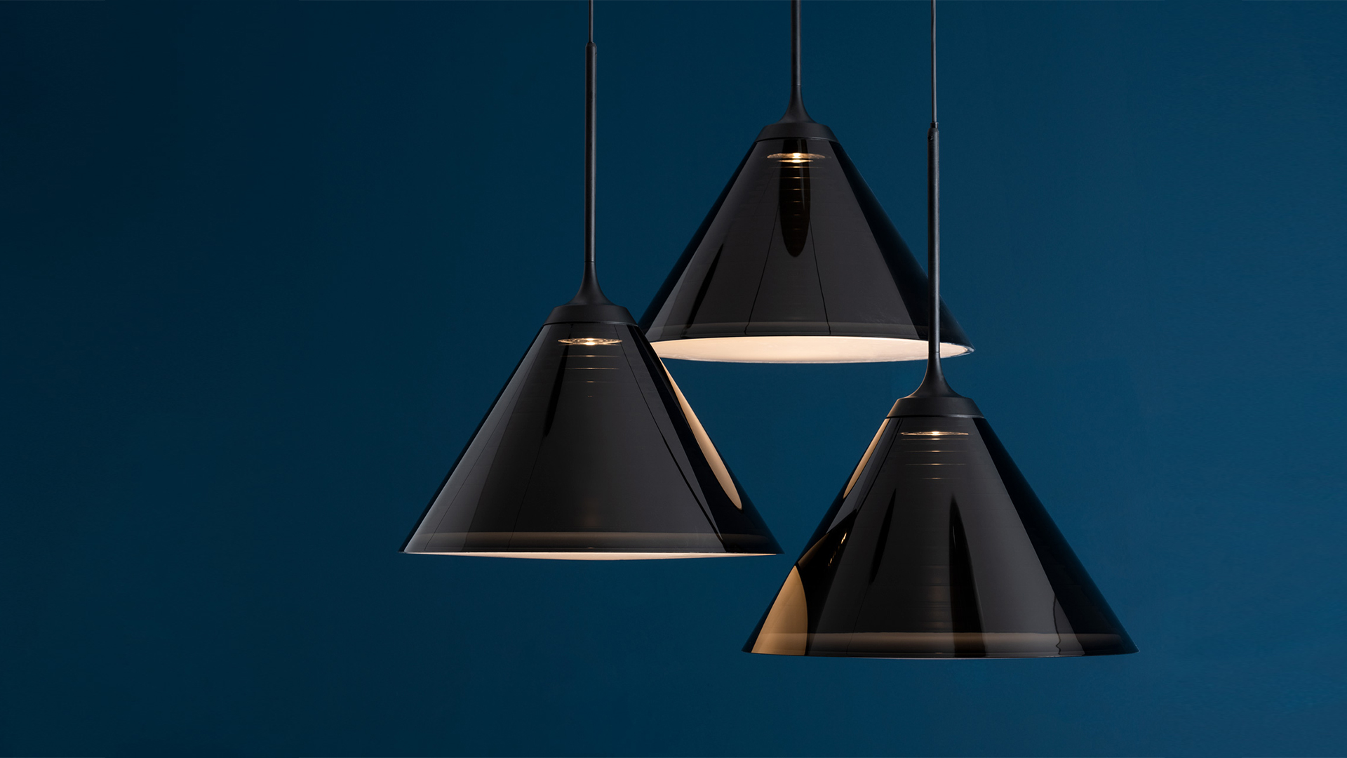 Interno moderno con lampade a sospensione nere Artemide Look at Me: gruppo di tre a sinistra, fila di quattro al centro, cinque su binario sopra il bancone