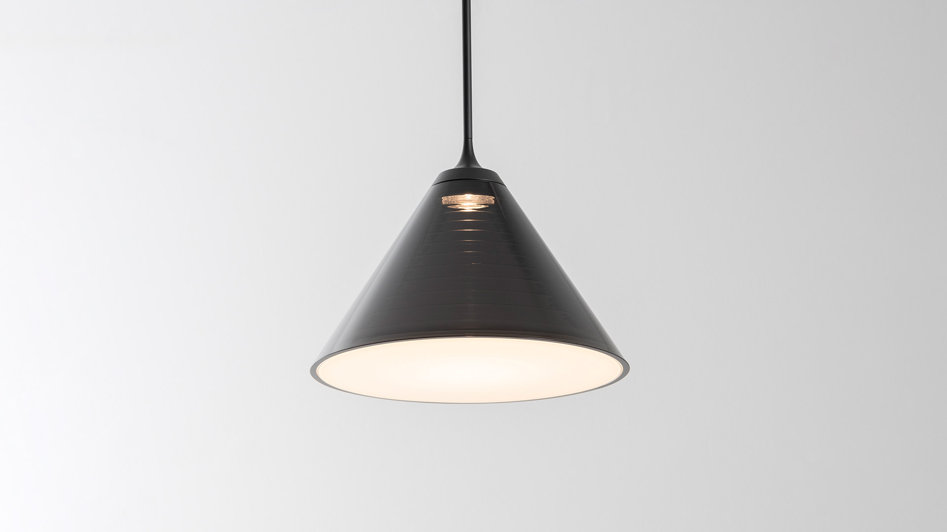 Due gruppi di lampade a sospensione Artemide Look at Me con paralumi conici scuri appesi a rosoni su sfondo scuro