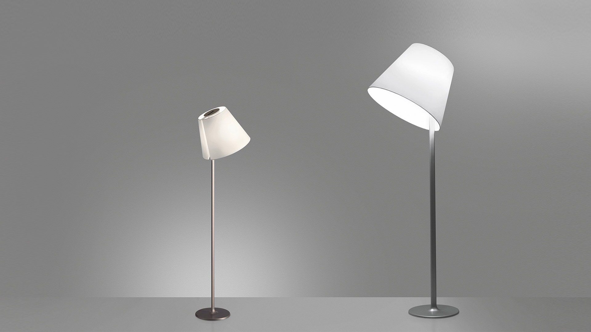 Due lampade da terra Artemide Melampo Terra con paralumi conici bianchi inclinabili su sottili pali metallici, nelle versioni piccola e grande