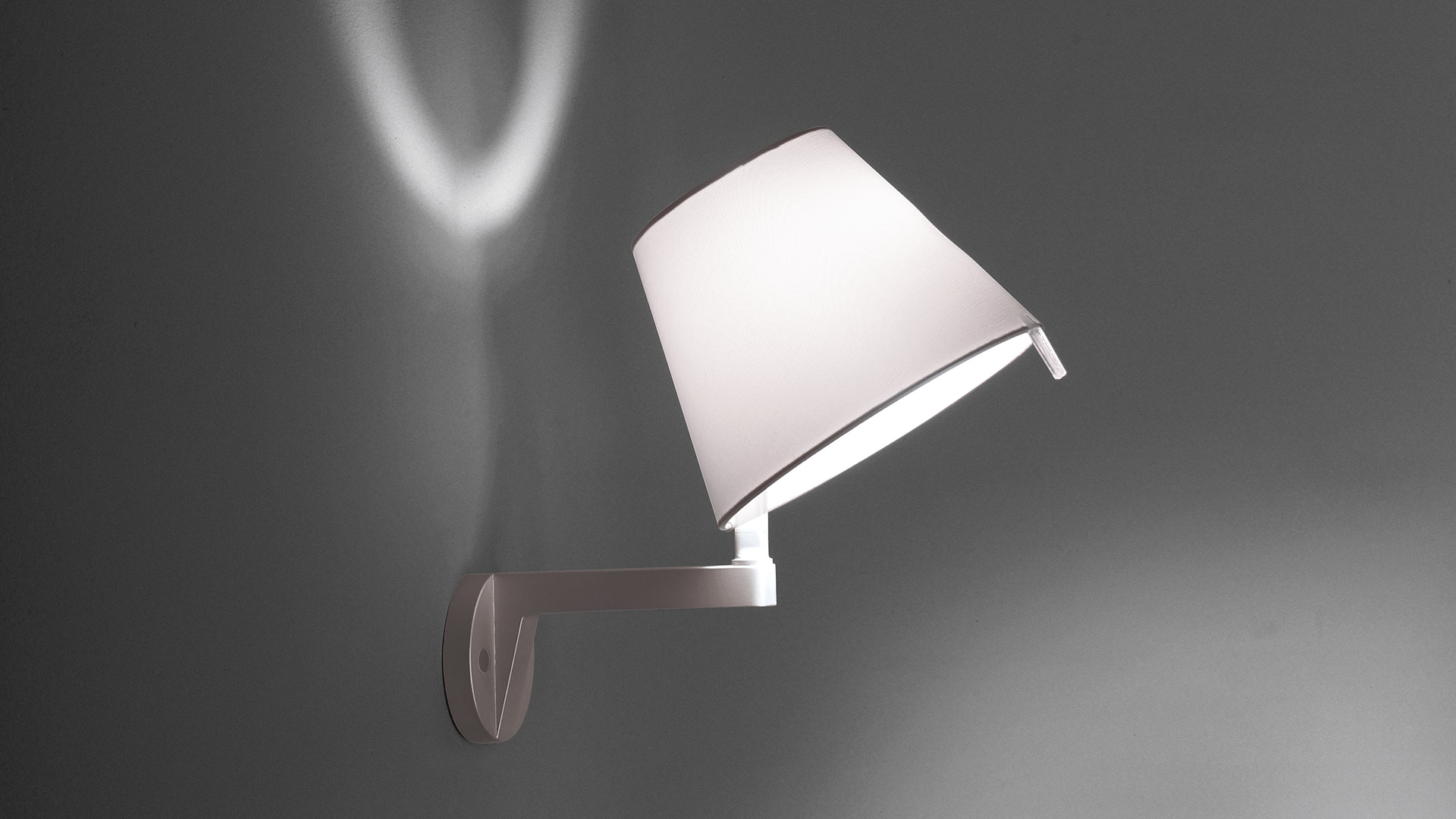 Lampada da parete Melampo Parete di Artemide, paralume conico bianco su testiera scura, con luce calda decorativa in camera da letto