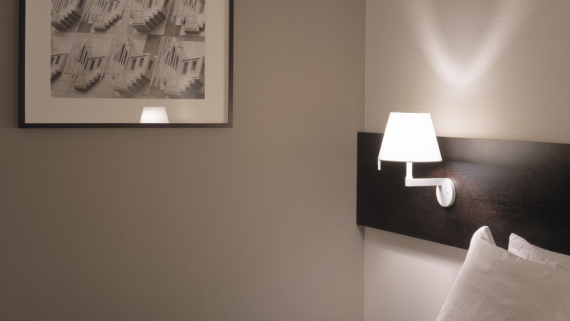 Lampada da parete Artemide Melampo Parete in bianco, con paralume conico in tessuto su braccio angolare, che proietta luce calda sulla parete.