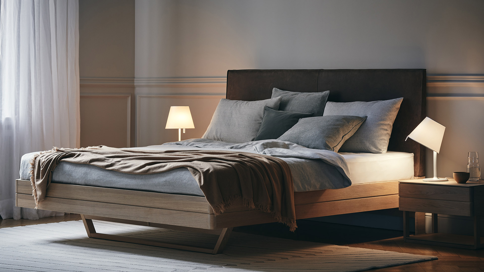 Lampada da tavolo Artemide Melampo Tavolo con paralume conico bianco su sottile stelo bianco, illuminata calorosamente su una scrivania in legno