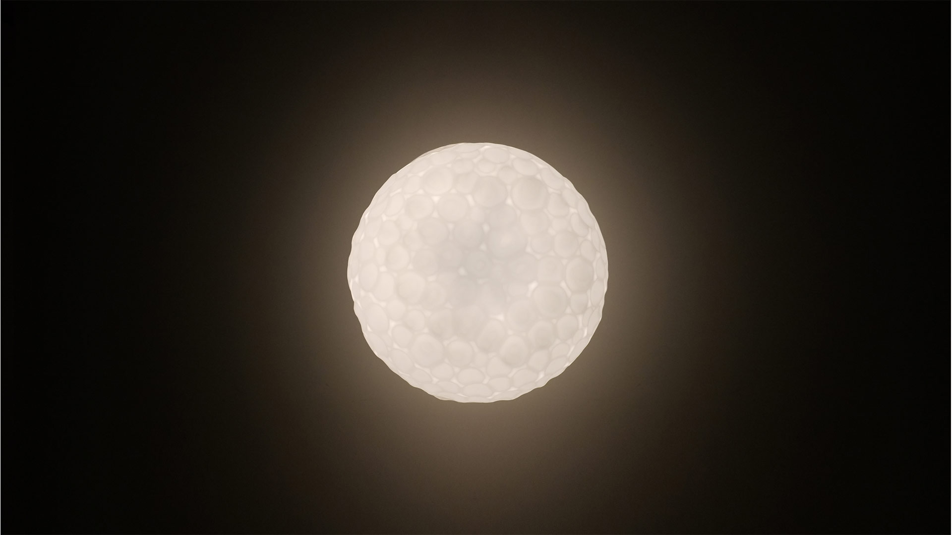Due lampade a sospensione Artemide Meteorite bianche di diverse dimensioni, con superficie testurizzata a crateri, sospese su sottili cavi su sfondo blu