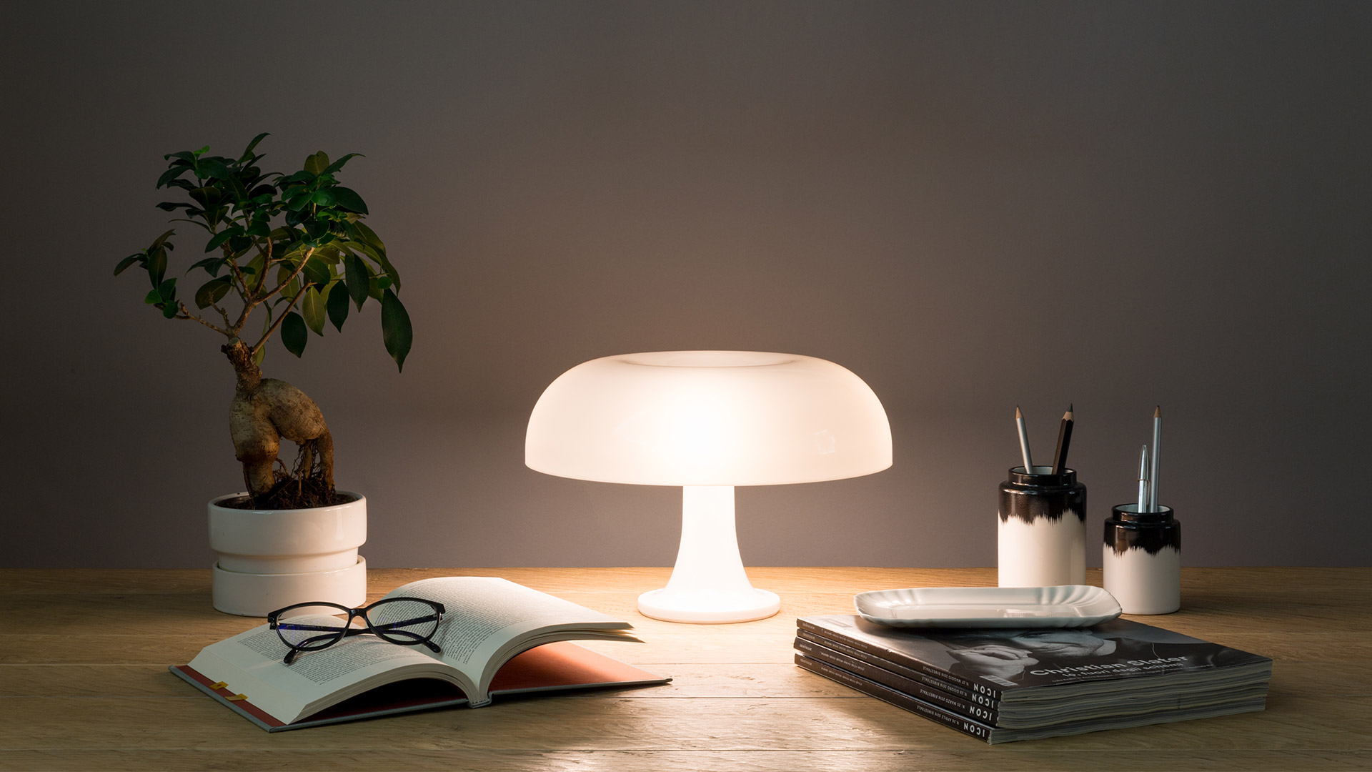 Otto lampade da tavolo Artemide Nessino in fila, che mostrano la gamma completa di colori: arancione, rosso, giallo, nero, bianco, blu, azzurro e verde