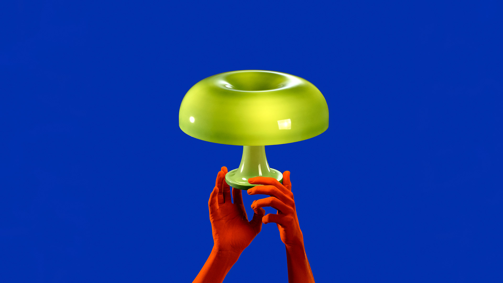 Due lampade da tavolo Artemide Nessino con paralume a fungo: arancione a sinistra, rossa a destra, su superficie bianca