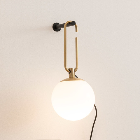 Lampada da parete Artemide NH Parete: staffa ad anello ovale in ottone su supporto nero a muro, con globo in vetro bianco opaco e cavo nero
