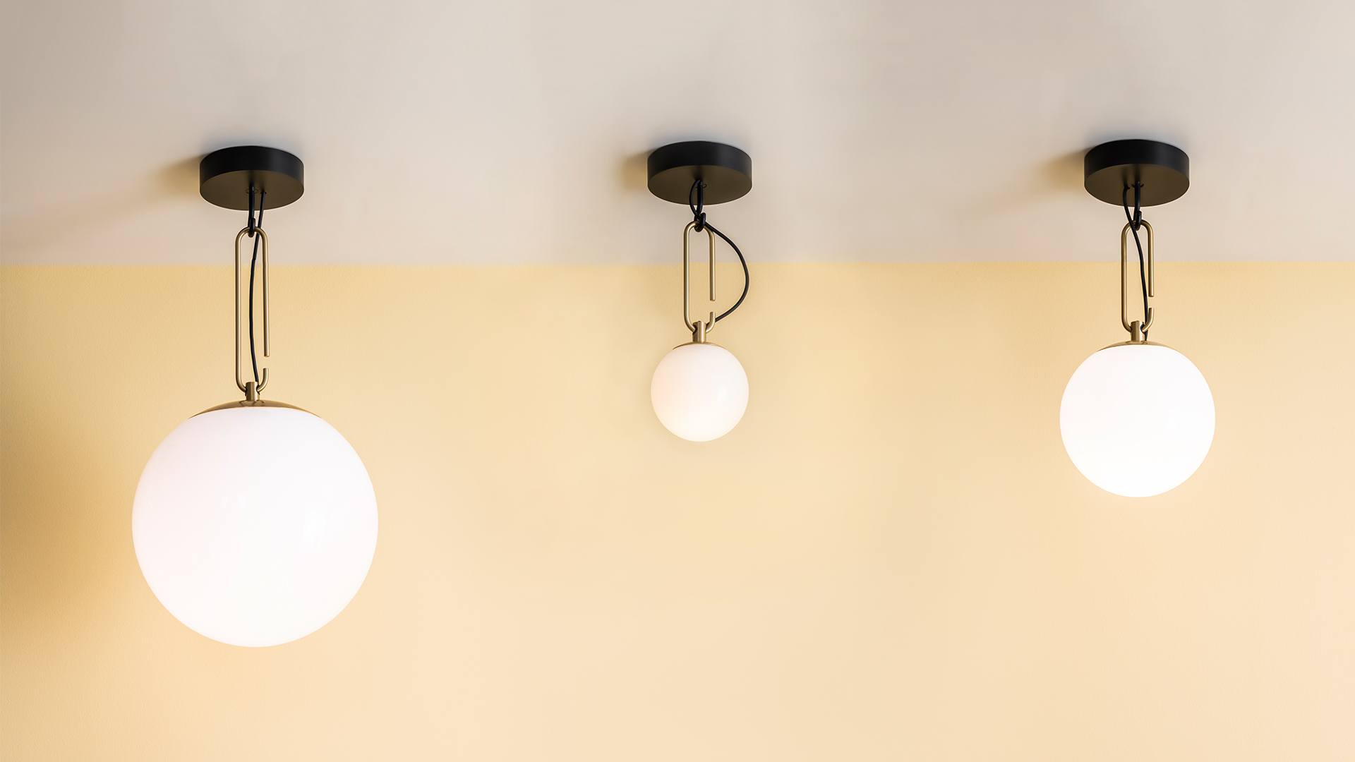 Dining room with glass table and wooden chairs under an Artemide pendant lamp with two white globe shades on a black metal arm.