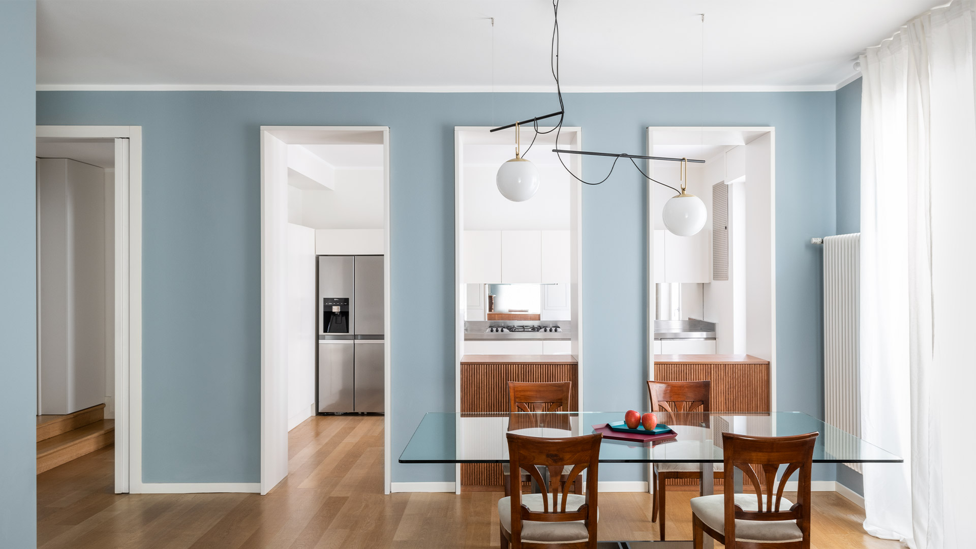 Three Artemide NH pendant lamps with opal white glass spheres in different sizes, brass fittings, suspended on black cords