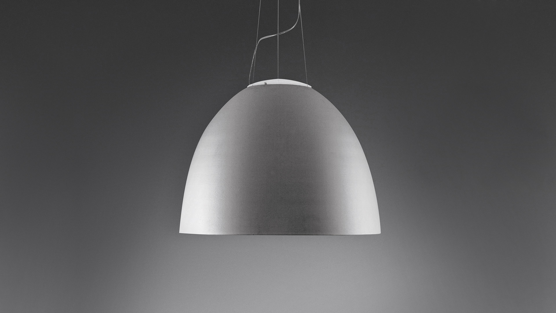 Tre lampade a sospensione Artemide Nur 1618 in nero opaco con interno dorato caldo, appese a diverse altezze su sottili cavi