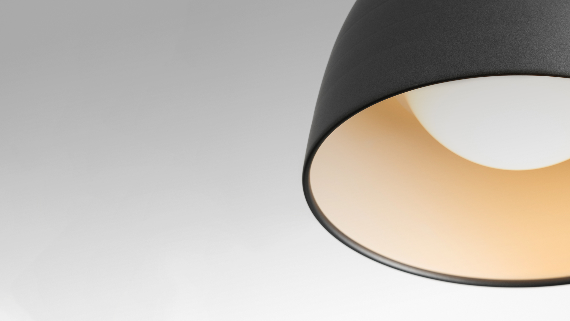 Lampada a sospensione Artemide Nur con ampio paralume a cupola in alluminio finitura grigia, luce calda verso il basso, sospesa da cavi bianchi