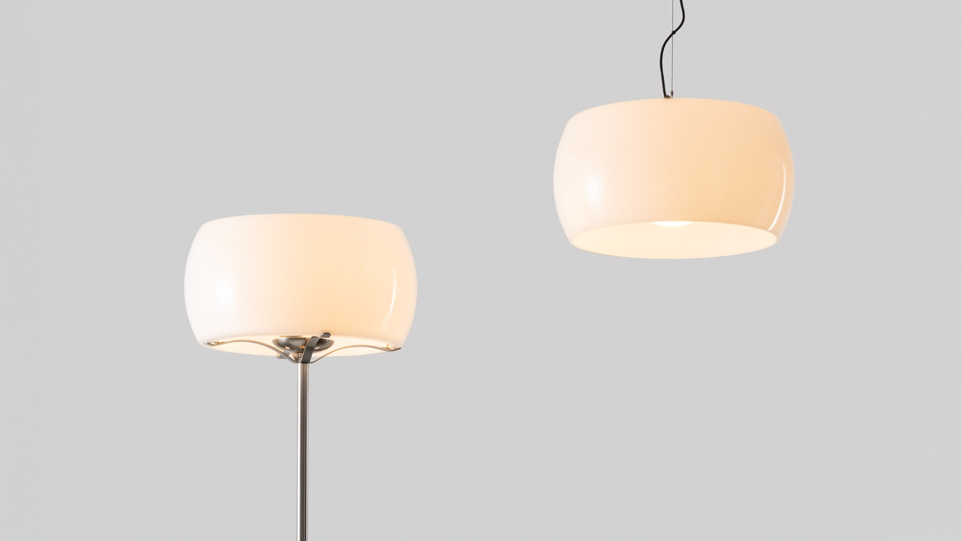 Artemide Omega pendant lamp with white rounded shade hanging above a minimalist desk with books, in a bright white room