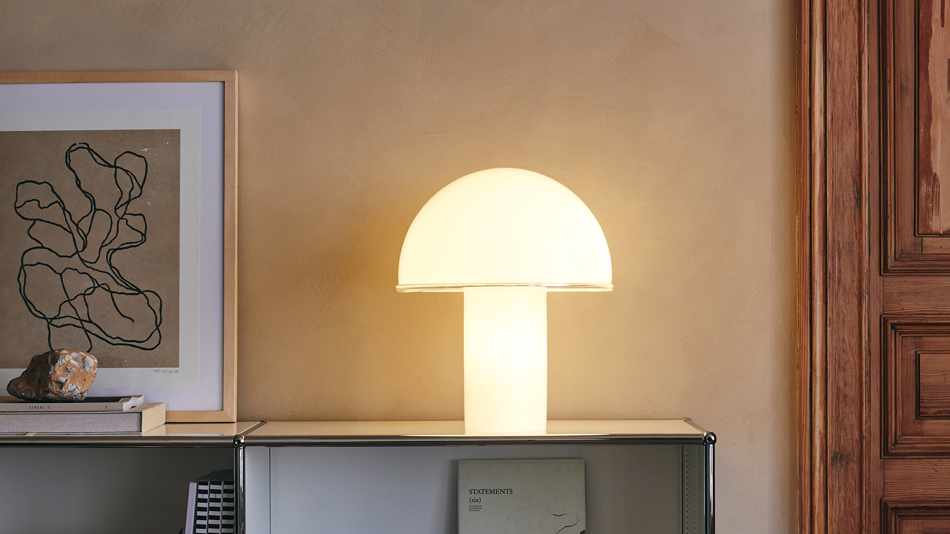 Two Artemide Onfale table lamps with white opal glass mushroom-shaped shades on cylindrical bases, displayed on a dark console table