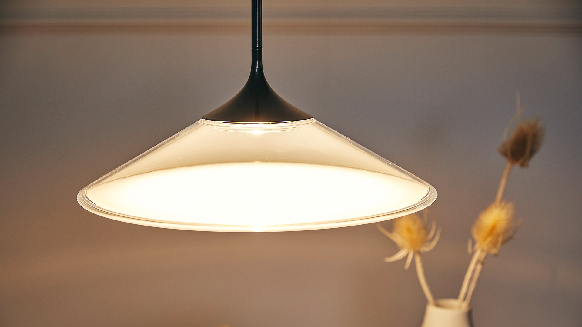 Orsa pendant lamp by Artemide: wide conical translucent shade emitting warm diffused light, suspended by a black stem