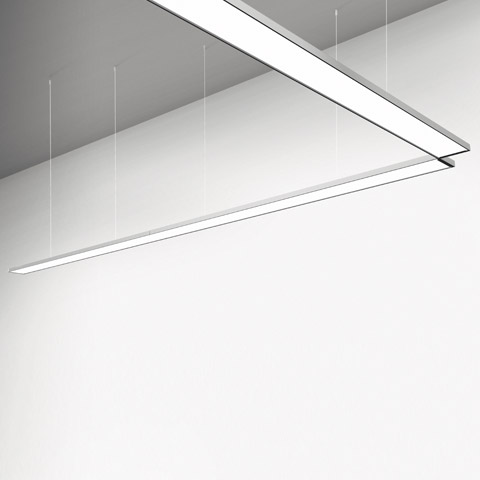 Artemide Pad System: eleganti luminarie lineari a LED sospese in alluminio, disposte in configurazione angolare, con luce bianca diffusa