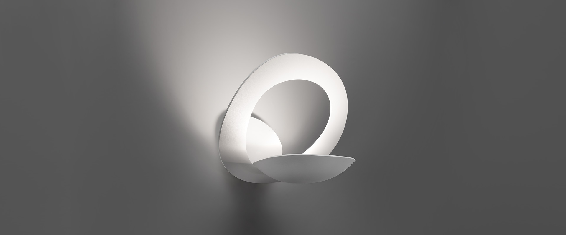 Artemide Pirce Parete wall lamp: sculptural white spiral-shaped diffuser mounted on wall, emitting soft ambient light